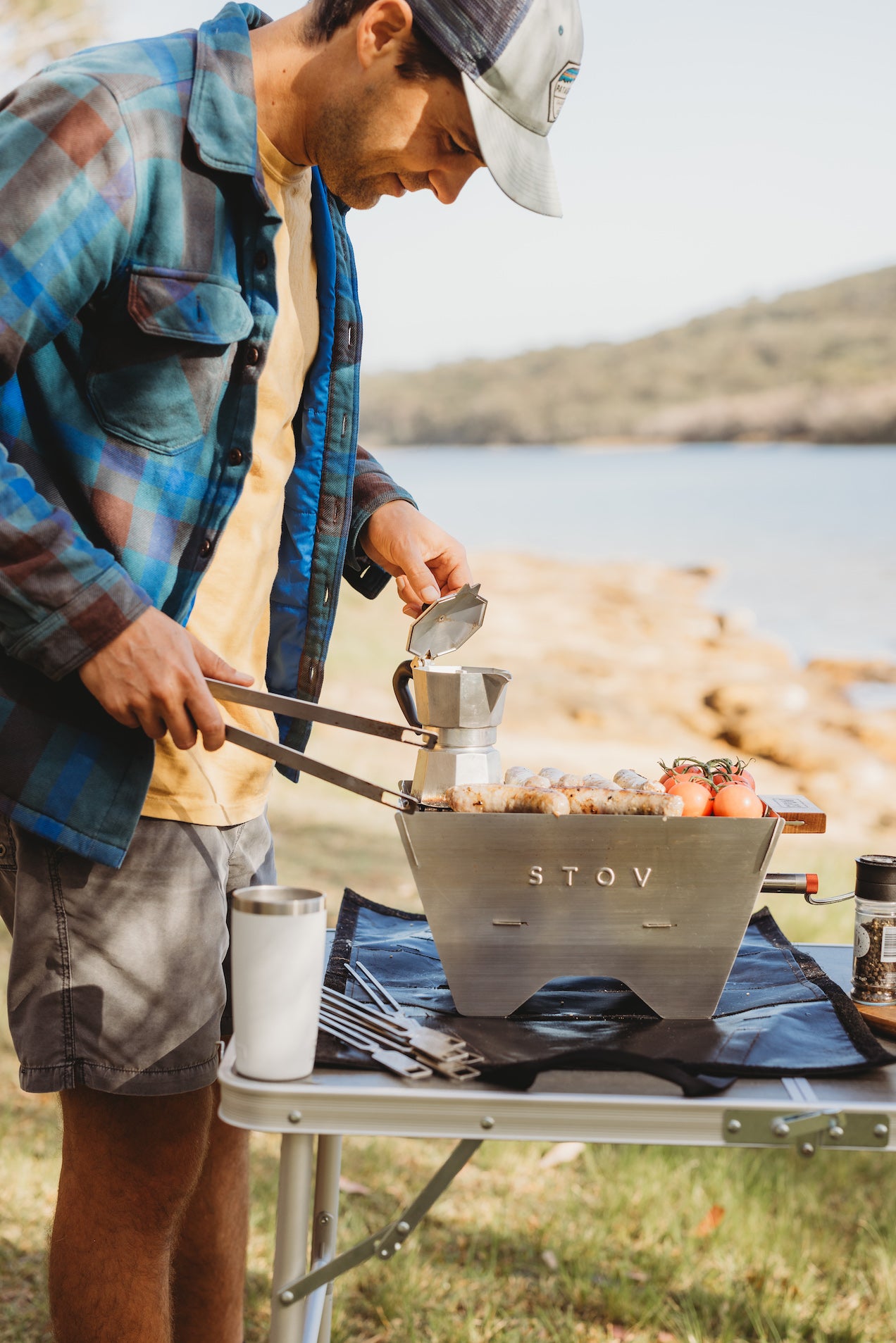 Cooking with a portable bbq on a clifftop or at the lake. The stov bbq is cooking delicious meals with ocean or lake views