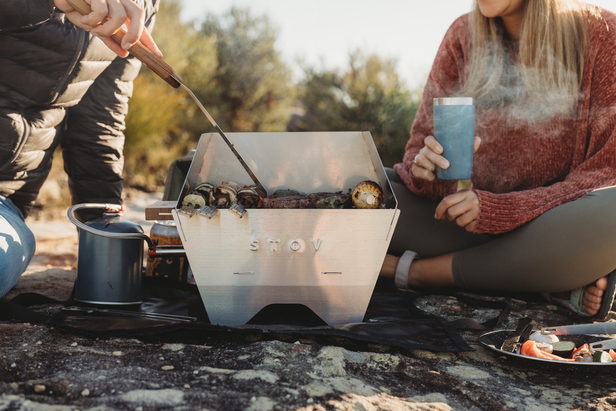 Two people cooking on compact STOV BBQ while outdoors